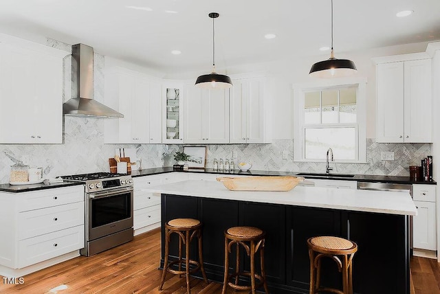 415 E Lavender Ave, Durham, NC 27704 - kitchen featuring stainless steel range with gas cooktop, wall chimney exhaust hood, a kitchen breakfast bar, tasteful backsplash, and recessed lighting