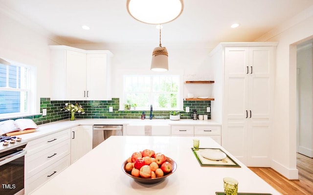415 E Lavender Ave, Durham, NC 27704 - kitchen featuring stainless steel appliances, white cabinets, light countertops, tasteful backsplash, and decorative light fixtures