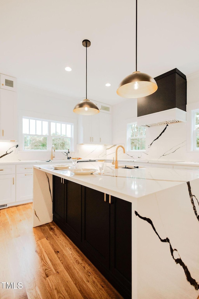 415 E Lavender Ave, Durham, NC 27704 - kitchen featuring white cabinetry, light wood finished floors, premium range hood, tasteful backsplash, and recessed lighting