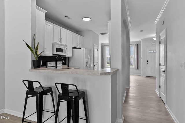 4536 Sugarbend Way, Raleigh, NC 27606 - kitchen with white appliances, light countertops, a kitchen breakfast bar, light wood finished floors, and white cabinetry