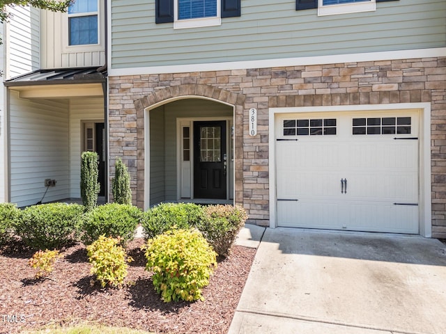 3810 Prince Noah Loop, Wake Forest, NC 27587 - doorway to property featuring stone siding, a standing seam roof, driveway, a metal roof, and an attached garage