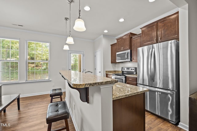 3810 Prince Noah Loop, Wake Forest, NC 27587 - kitchen with appliances with stainless steel finishes, crown molding, an island with sink, light stone countertops, and dark wood-style floors