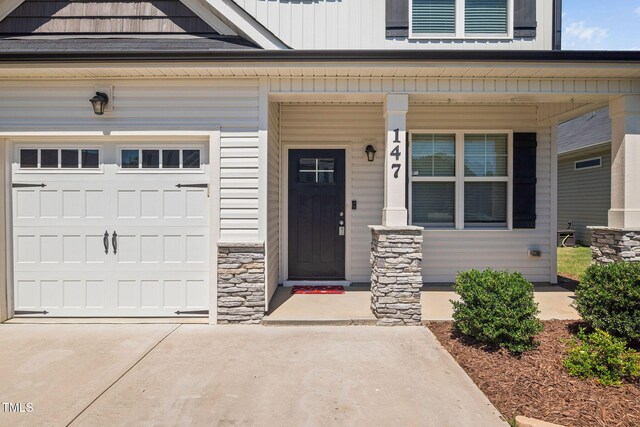 147 Sunfish St, Smithfield, NC 27577 - view of exterior entry with covered porch, a garage, concrete driveway, and stone siding