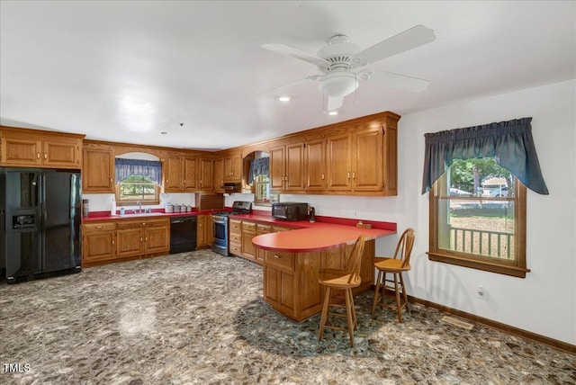 140 Maryland Dr, Manson, NC 27553 - kitchen featuring black appliances, a peninsula, brown cabinetry, a kitchen bar, and a ceiling fan