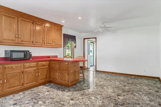 140 Maryland Dr, Manson, NC 27553 - kitchen featuring black microwave, ceiling fan, a peninsula, brown cabinetry, and a kitchen bar