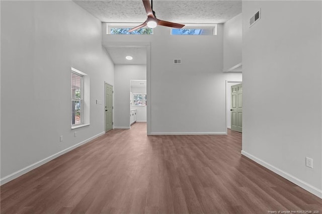 12741 Birchwood Cir, Laurinburg, NC 28352 - unfurnished living room featuring a towering ceiling, a ceiling fan, wood finished floors, and a textured ceiling