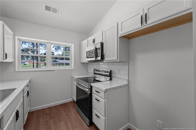 12741 Birchwood Cir, Laurinburg, NC 28352 - kitchen featuring stainless steel appliances, vaulted ceiling, dark wood-style floors, light countertops, and tasteful backsplash