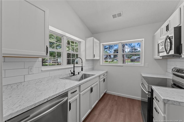 12741 Birchwood Cir, Laurinburg, NC 28352 - kitchen with appliances with stainless steel finishes, dark wood-style floors, vaulted ceiling, tasteful backsplash, and white cabinetry