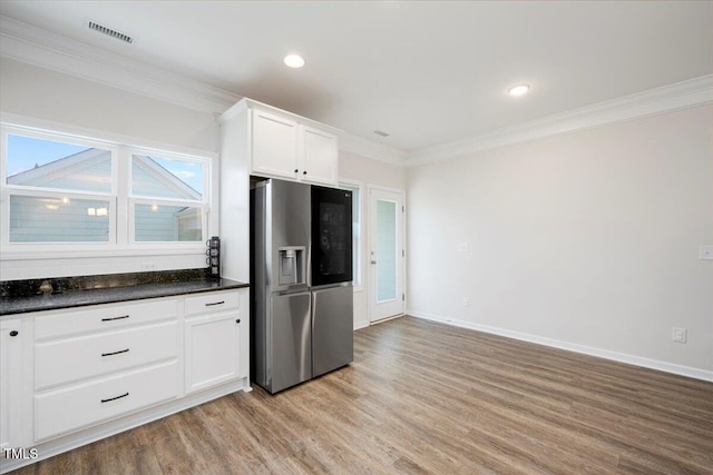 1125 Russet Ln, Apex, NC 27523 - kitchen with stainless steel fridge, crown molding, light wood-type flooring, dark countertops, and white cabinetry
