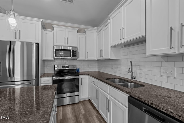 310 Oak Pointe Cir E, Lumberton, NC 28358 - kitchen with appliances with stainless steel finishes, white cabinets, dark stone counters, dark wood-type flooring, and tasteful backsplash