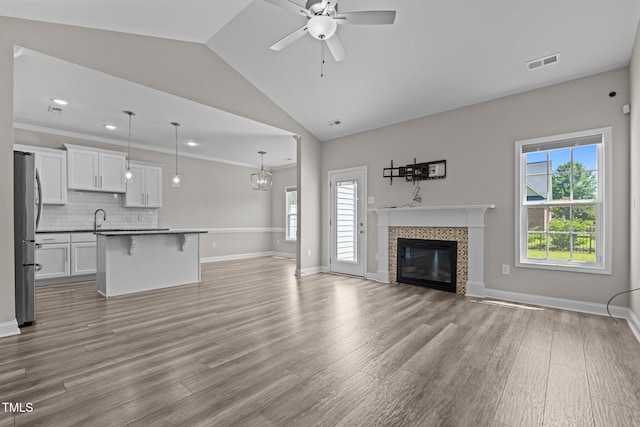 310 Oak Pointe Cir E, Lumberton, NC 28358 - unfurnished living room featuring plenty of natural light, ceiling fan, vaulted ceiling, a tile fireplace, and light wood-type flooring