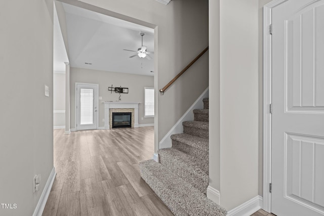 310 Oak Pointe Cir E, Lumberton, NC 28358 - staircase with ceiling fan, a glass covered fireplace, and wood finished floors