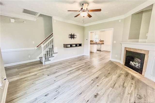 37 Annapolis Rd, Cameron, NC 28326 - unfurnished living room featuring crown molding, light wood-style flooring, a tile fireplace, a ceiling fan, and stairway