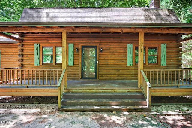 3263 S Jim Minor Rd, Haw River, NC 27258 - view of exterior entry with log siding, a chimney, and covered porch