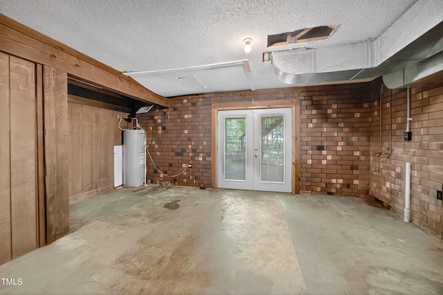 3263 S Jim Minor Rd, Haw River, NC 27258 - below grade area featuring water heater, french doors, a textured ceiling, and brick wall
