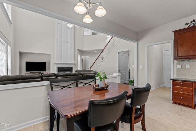 308 Sutton Glen Dr, Apex, NC 27523 - dining space with a chandelier, a fireplace, stairs, and light tile patterned floors