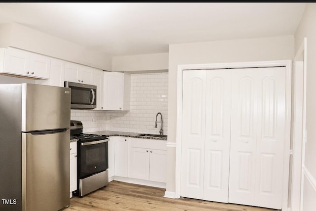 621 Reservoir St, Durham, NC 27703 - kitchen featuring stainless steel appliances, white cabinetry, light wood-type flooring, decorative backsplash, and dark stone counters