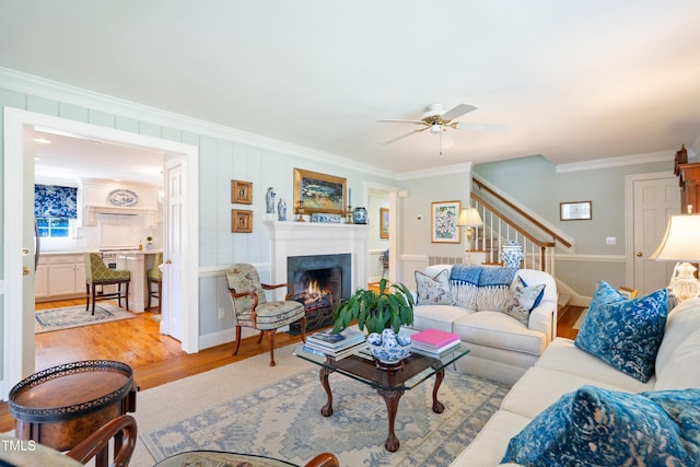 1610 Ridge Rd, Raleigh, NC 27607 - living room with a ceiling fan, crown molding, wood finished floors, a warm lit fireplace, and stairs