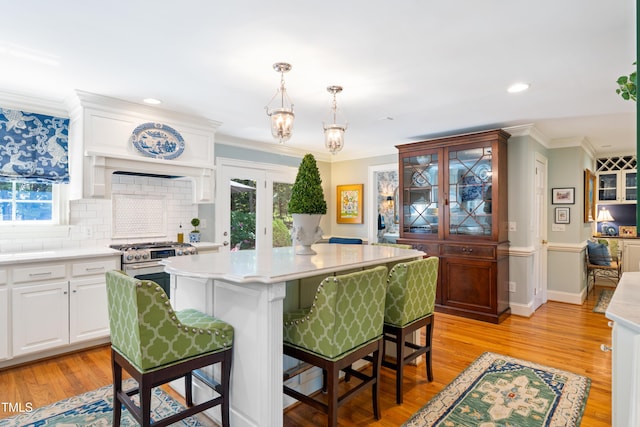 1610 Ridge Rd, Raleigh, NC 27607 - kitchen with light countertops, tasteful backsplash, crown molding, white cabinetry, and a kitchen bar