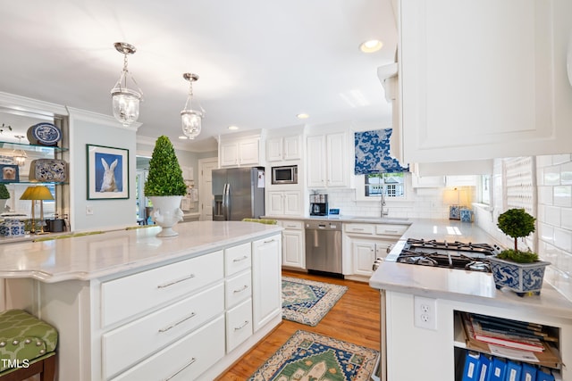 1610 Ridge Rd, Raleigh, NC 27607 - kitchen featuring appliances with stainless steel finishes, white cabinetry, backsplash, light wood finished floors, and hanging light fixtures