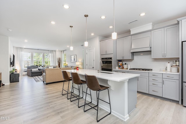 2866 Hunter Woods Dr, Apex, NC 27502 - kitchen with gray cabinets, a breakfast bar area, light countertops, appliances with stainless steel finishes, and light wood-style floors