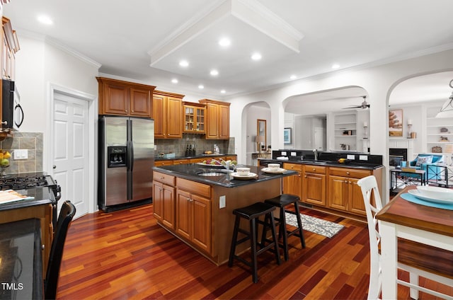 5106 Stockton Way, Durham, NC 27707 - kitchen with stainless steel appliances, ornamental molding, brown cabinets, a fireplace, and dark wood-type flooring