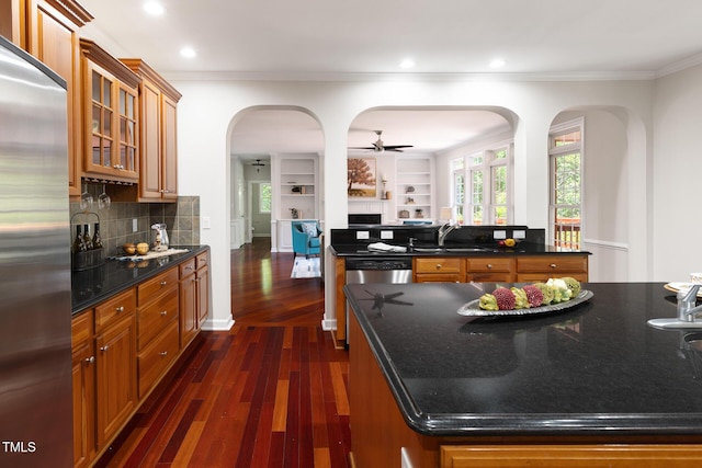 5106 Stockton Way, Durham, NC 27707 - kitchen featuring appliances with stainless steel finishes, brown cabinets, dark wood-type flooring, arched walkways, and crown molding