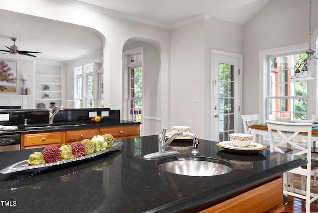 5106 Stockton Way, Durham, NC 27707 - kitchen featuring brown cabinetry, healthy amount of natural light, crown molding, arched walkways, and dark stone countertops