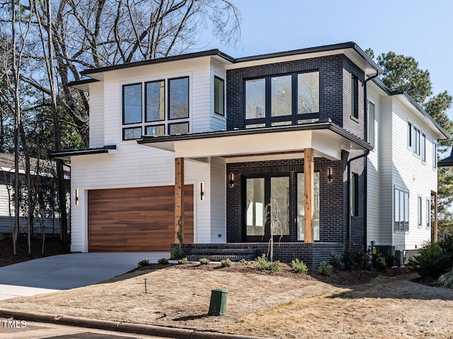1009 Parker St, Raleigh, NC 27607 - modern home with a porch, an attached garage, driveway, and brick siding