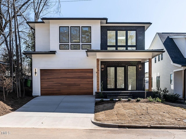 1009 Parker St, Raleigh, NC 27607 - contemporary home featuring a garage, a porch, concrete driveway, and brick siding
