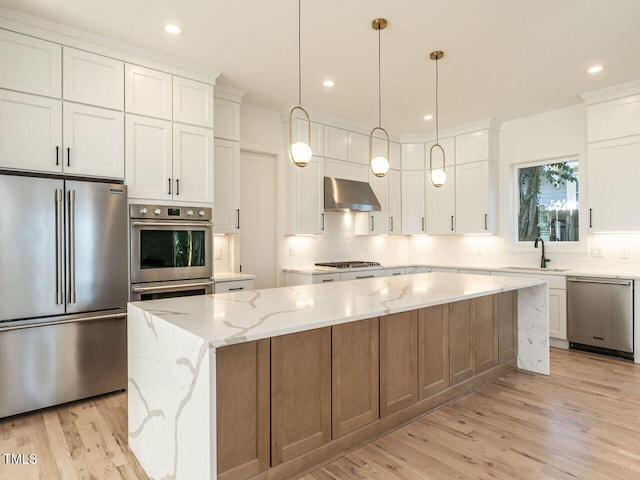 1009 Parker St, Raleigh, NC 27607 - kitchen with stainless steel appliances, wall chimney exhaust hood, tasteful backsplash, a kitchen island, and light wood-type flooring