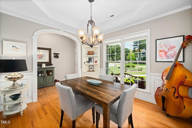 904 E Ivy Valley Dr, Fuquay Varina, NC 27526 - dining room featuring a chandelier, light wood-style flooring, a raised ceiling, crown molding, and a wainscoted wall
