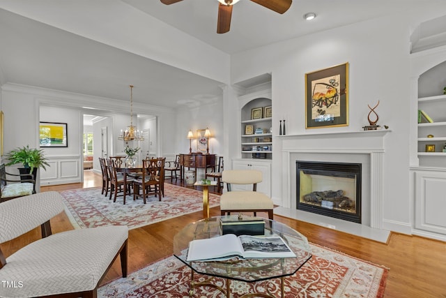 145 Cofield Cir, Durham, NC 27707 - living area with built in shelves, wood finished floors, a ceiling fan, a glass covered fireplace, and crown molding