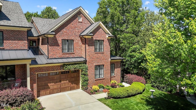 145 Cofield Cir, Durham, NC 27707 - view of front of home with a standing seam roof, brick siding, an attached garage, driveway, and roof with shingles
