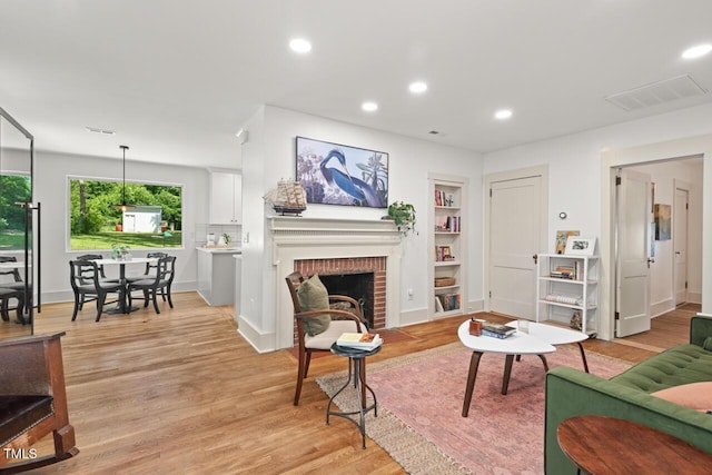 2410 Huron St, Durham, NC 27707 - living room featuring light wood-style floors, recessed lighting, built in features, and a brick fireplace