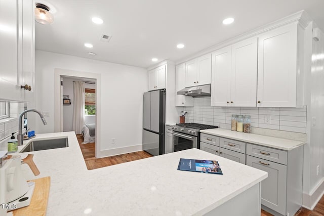 2410 Huron St, Durham, NC 27707 - kitchen featuring appliances with stainless steel finishes, under cabinet range hood, wood finished floors, tasteful backsplash, and recessed lighting