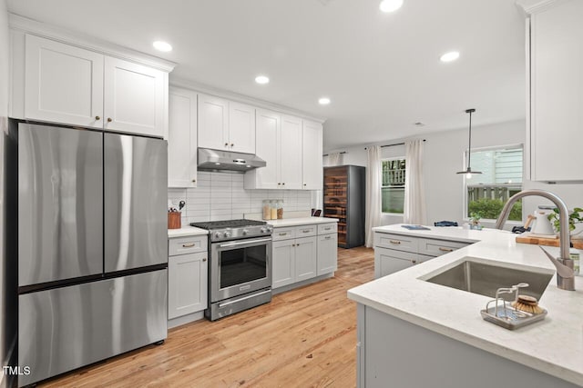 2410 Huron St, Durham, NC 27707 - kitchen with appliances with stainless steel finishes, under cabinet range hood, tasteful backsplash, recessed lighting, and light wood-type flooring