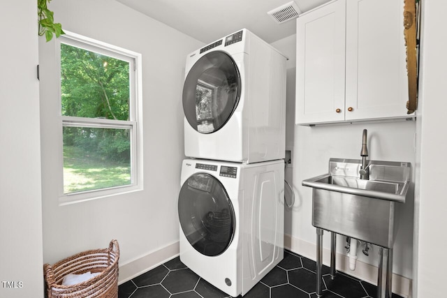 2410 Huron St, Durham, NC 27707 - washroom with cabinet space, stacked washer / dryer, healthy amount of natural light, and dark tile patterned floors