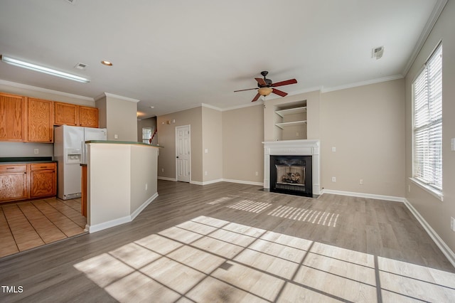 2261 Plum Frost Dr, Raleigh, NC 27603 - kitchen with white fridge with ice dispenser, light wood-type flooring, ceiling fan, plenty of natural light, and crown molding