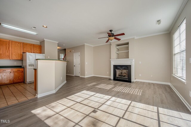 2261 Plum Frost Dr, Raleigh, NC 27603 - kitchen with white fridge with ice dispenser, light wood-type flooring, ceiling fan, plenty of natural light, and crown molding