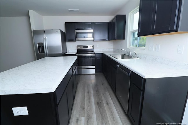 96 Cutty Way, Lillington, NC 27546 - kitchen with appliances with stainless steel finishes, light wood finished floors, a kitchen island, light countertops, and dark cabinets
