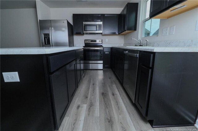 96 Cutty Way, Lillington, NC 27546 - kitchen with stainless steel appliances, dark cabinetry, and light wood-style flooring