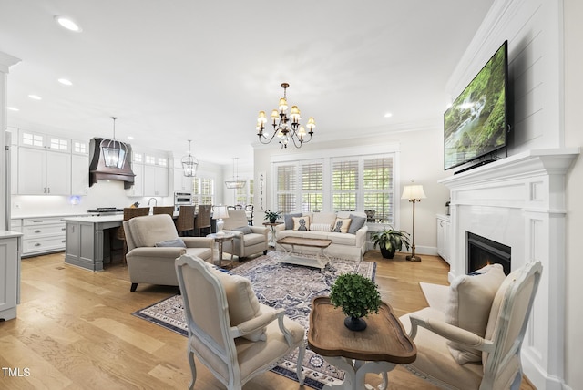 175 Stonecrest Way, Pittsboro, NC 27312 - living room with a chandelier, recessed lighting, light wood-style flooring, crown molding, and a fireplace with flush hearth