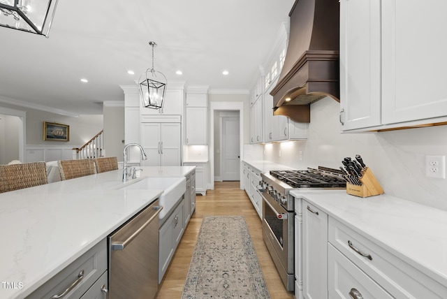 175 Stonecrest Way, Pittsboro, NC 27312 - kitchen featuring appliances with stainless steel finishes, custom exhaust hood, crown molding, gray cabinets, and light wood-style flooring
