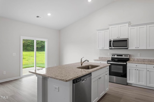 3837 Ava Dr, Bailey, NC 27807 - kitchen with stainless steel appliances, light wood finished floors, an island with sink, vaulted ceiling, and white cabinets