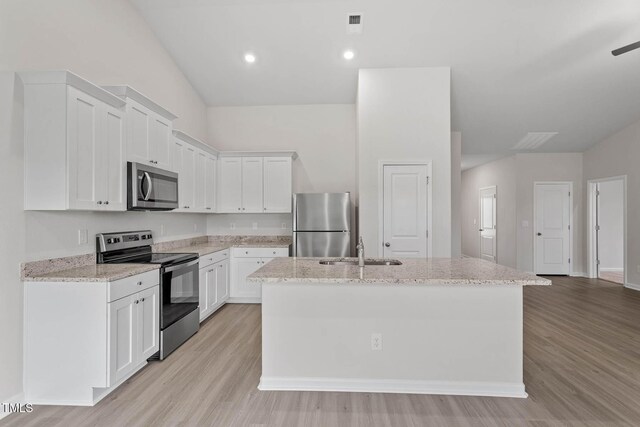 3837 Ava Dr, Bailey, NC 27807 - kitchen featuring stainless steel appliances, a kitchen island with sink, light wood-style flooring, white cabinetry, and light stone counters