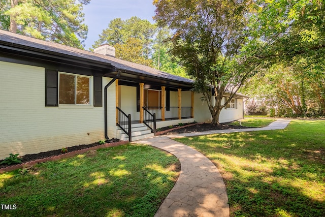 944 Athens Dr, Raleigh, NC 27606 - view of front of property with covered porch, a front yard, a chimney, and brick siding