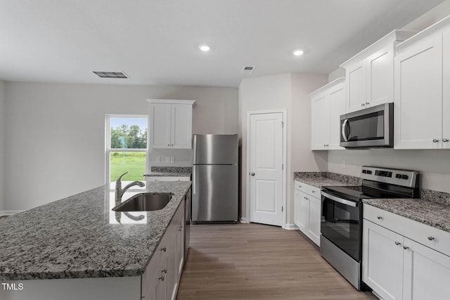 3930 Needham Rd, Bailey, NC 27807 - kitchen featuring appliances with stainless steel finishes, white cabinets, recessed lighting, an island with sink, and light wood-style flooring