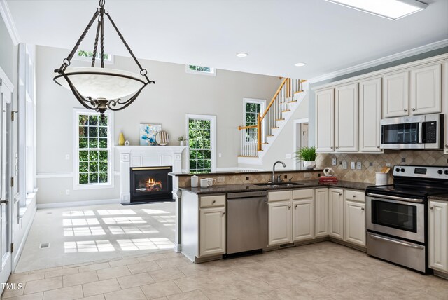 5940 Dahlberg Dr, Raleigh, NC 27603 - kitchen featuring stainless steel appliances, backsplash, a peninsula, recessed lighting, and a glass covered fireplace
