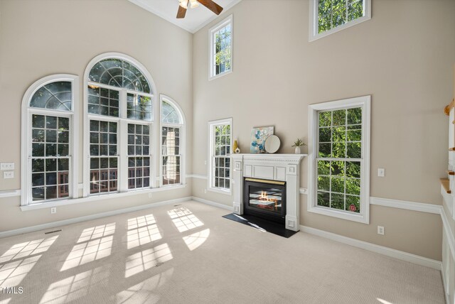 5940 Dahlberg Dr, Raleigh, NC 27603 - unfurnished living room featuring a ceiling fan, carpet flooring, a fireplace with flush hearth, ornamental molding, and high vaulted ceiling
